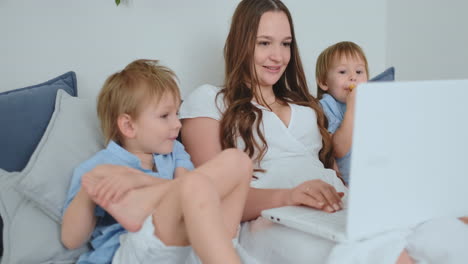 Mom-and-kids-laugh-sitting-in-front-of-the-laptop-and-look-at-the-screen